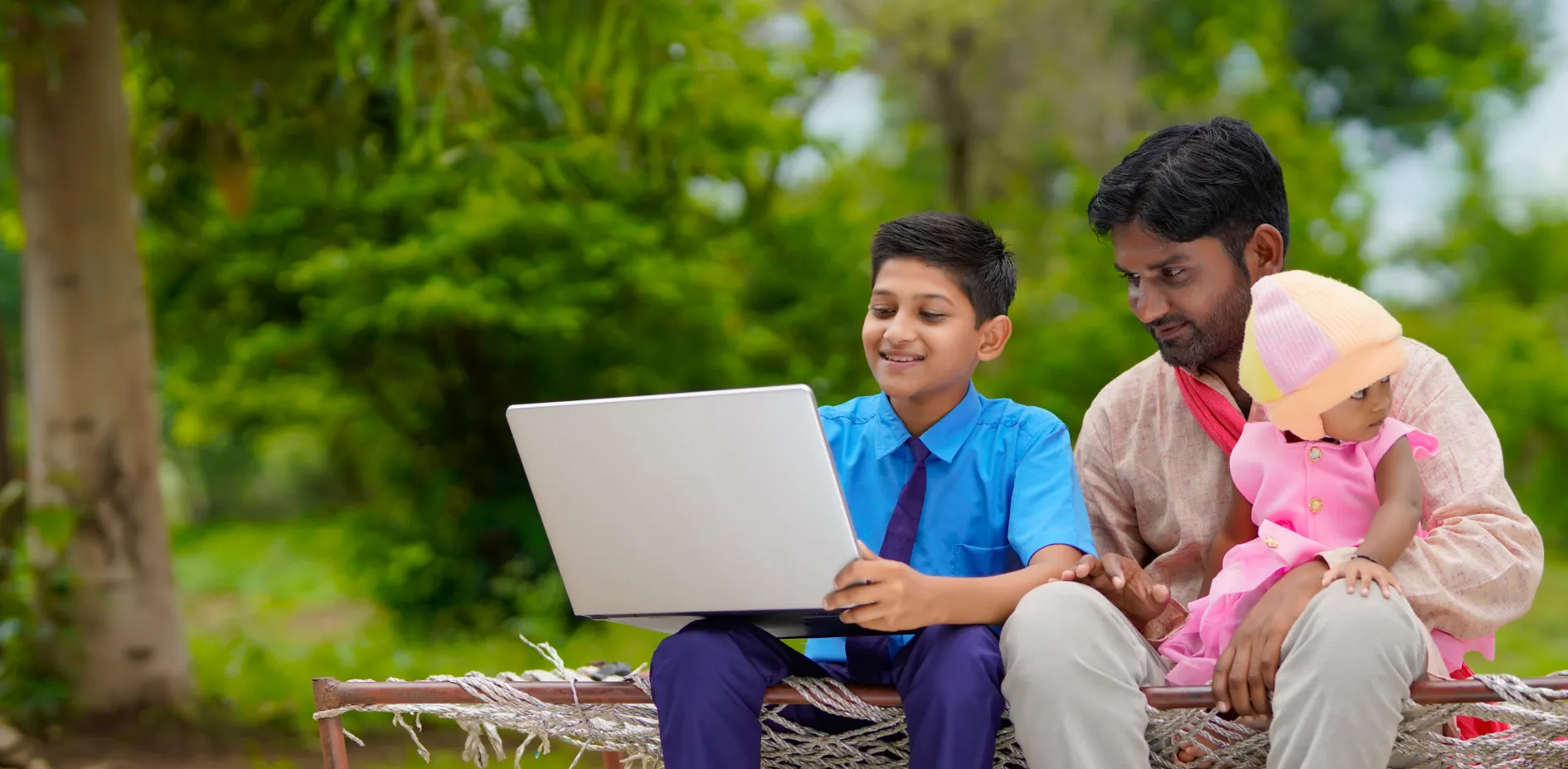 Student learning on a laptop outdoors with his family