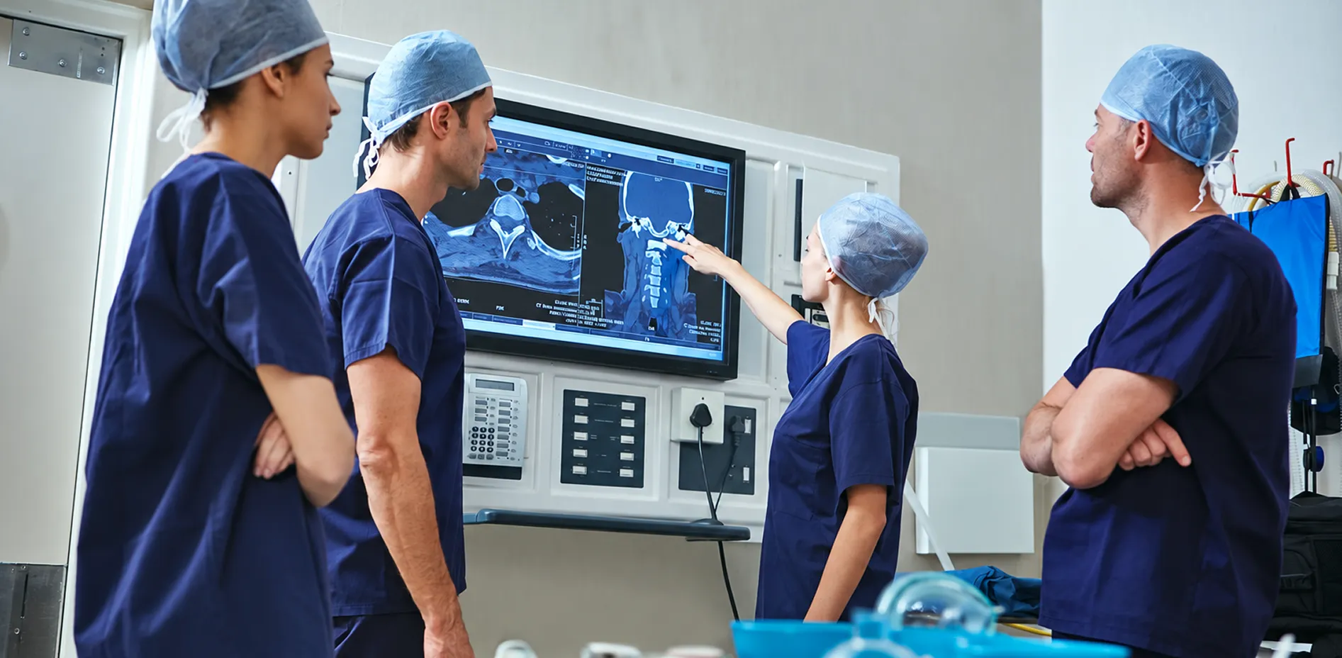 Surgical team reviewing CT scans on an operating theatre display