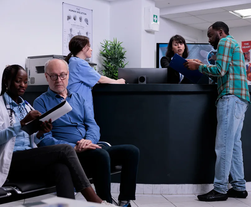 Hospital reception desk with staff assisting patients