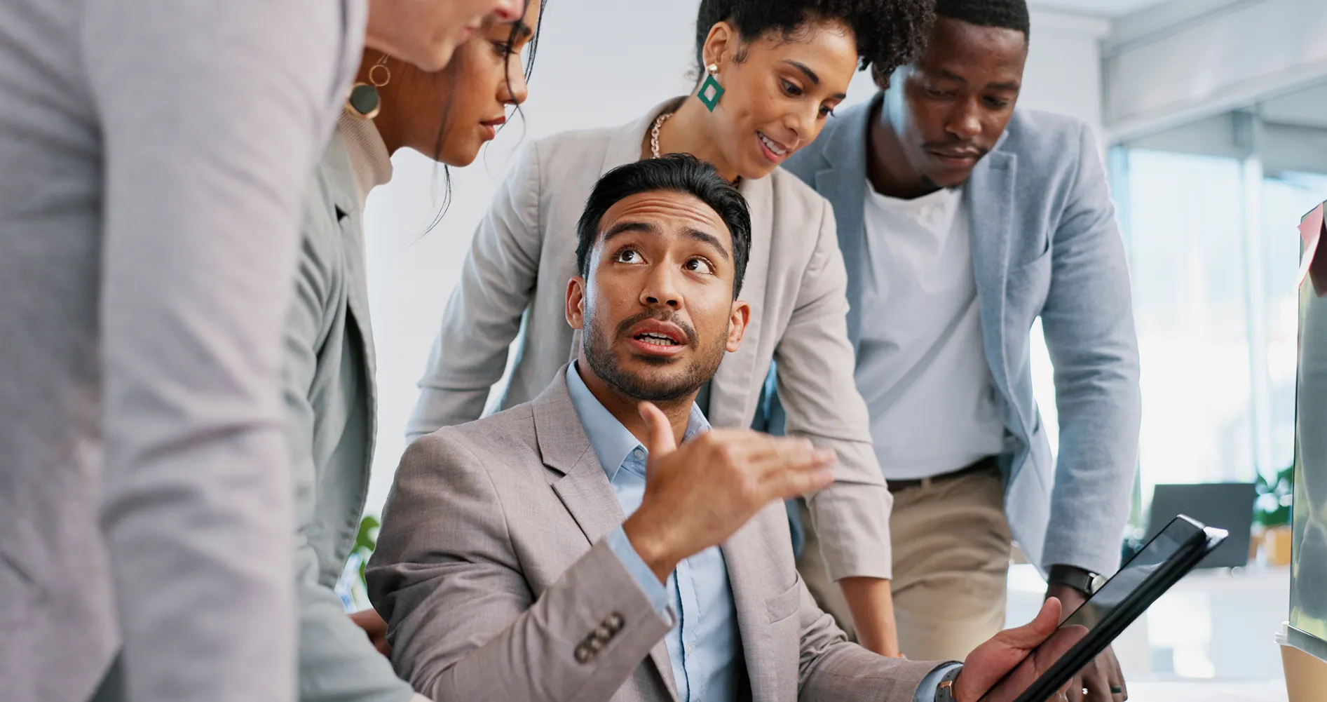 Professional explaining ideas to colleagues gathered around him in an office