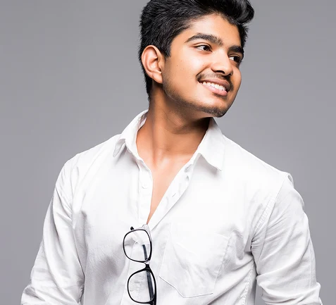 Smiling young man in a white shirt with glasses hooked on his pocket