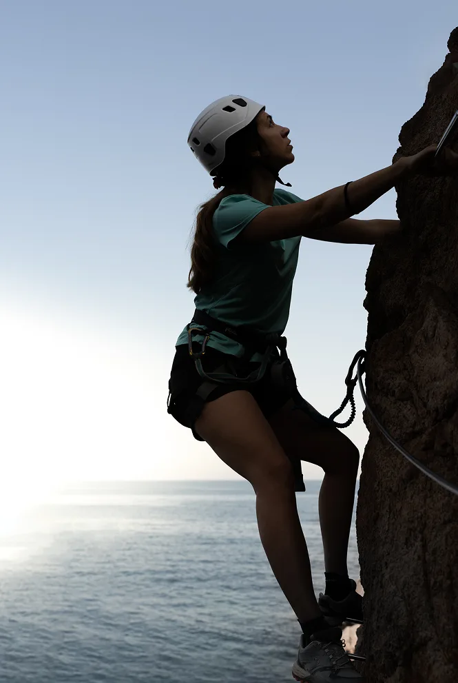Climber scaling a sea cliff with a safety line