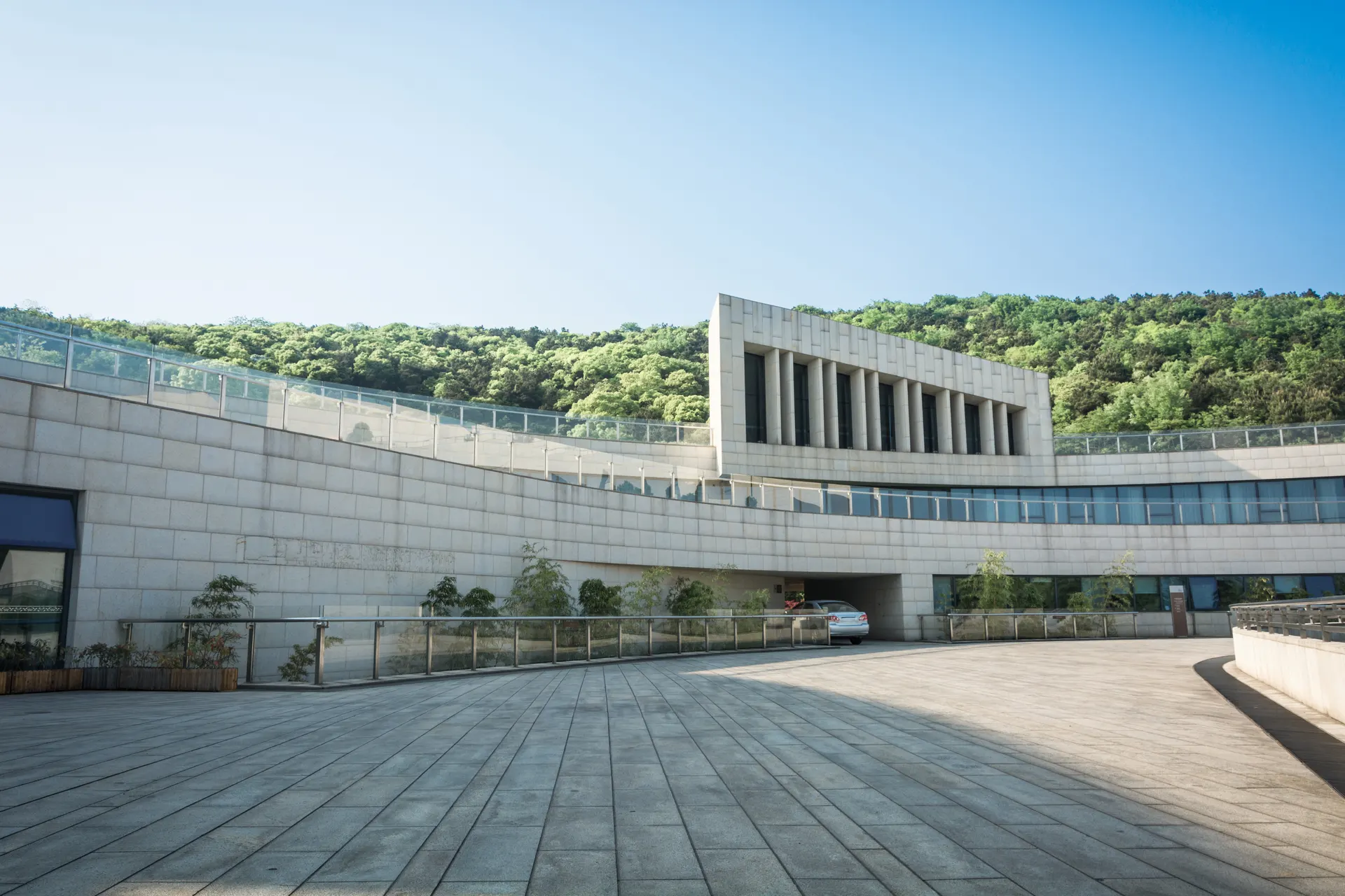 Modern hospital building with a stone facade set against a green hillside