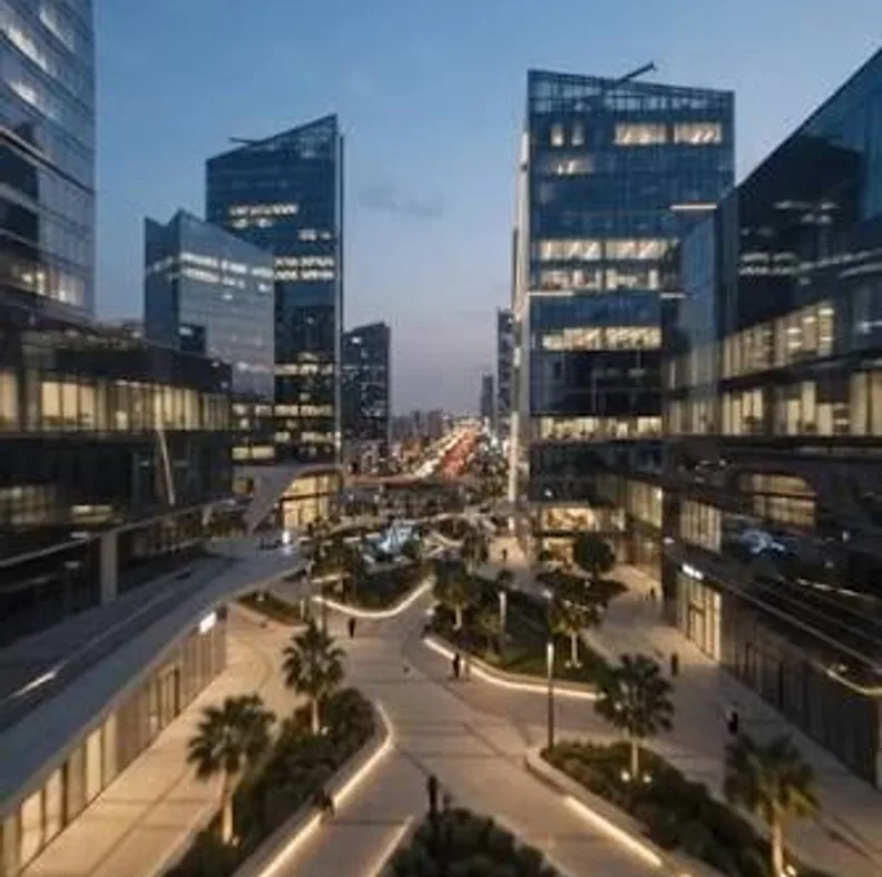 Riyadh office district at twilight with glass towers and a lit palm-lined plaza
