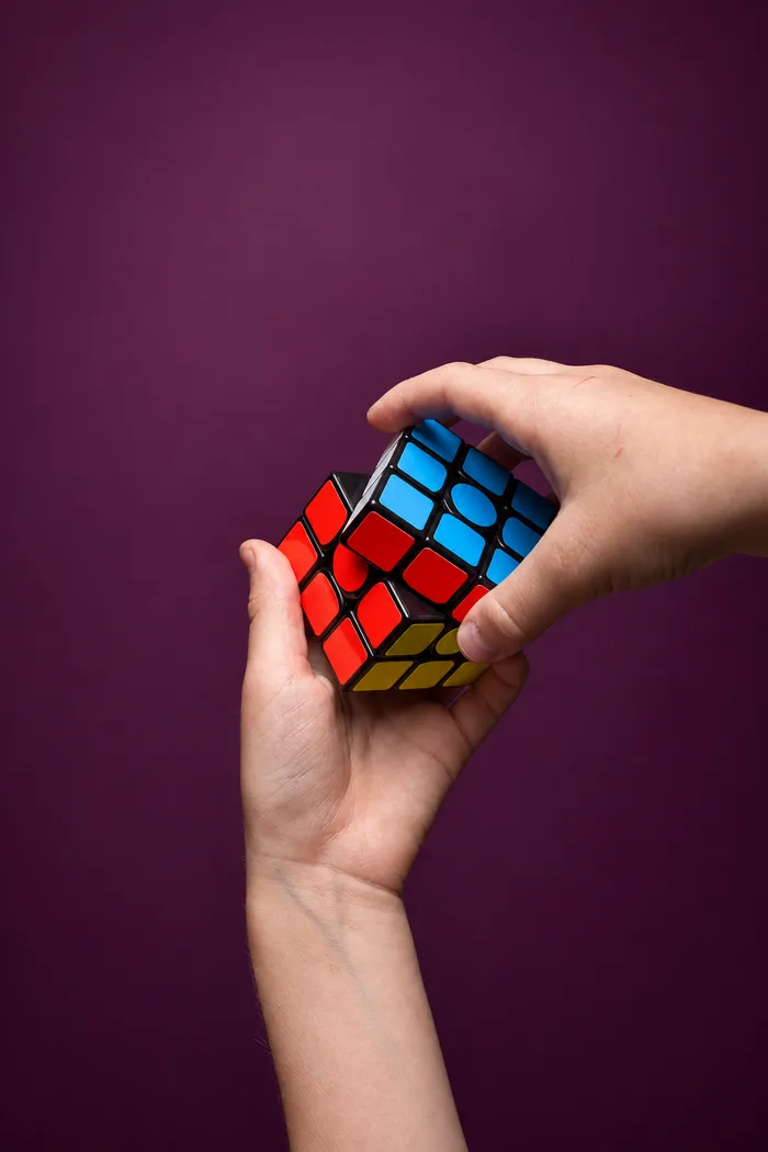 Hands turning a Rubik’s cube against a plum background