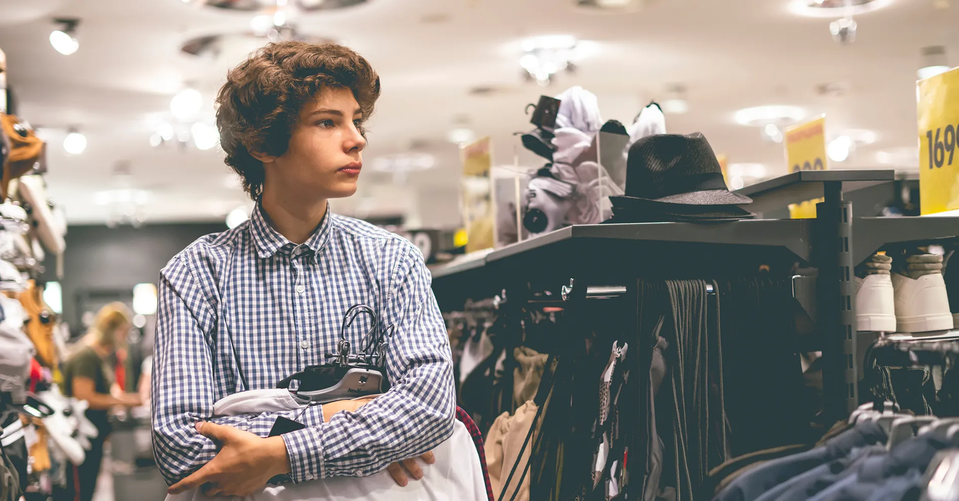 Young shopper holding clothes on hangers in a fashion store